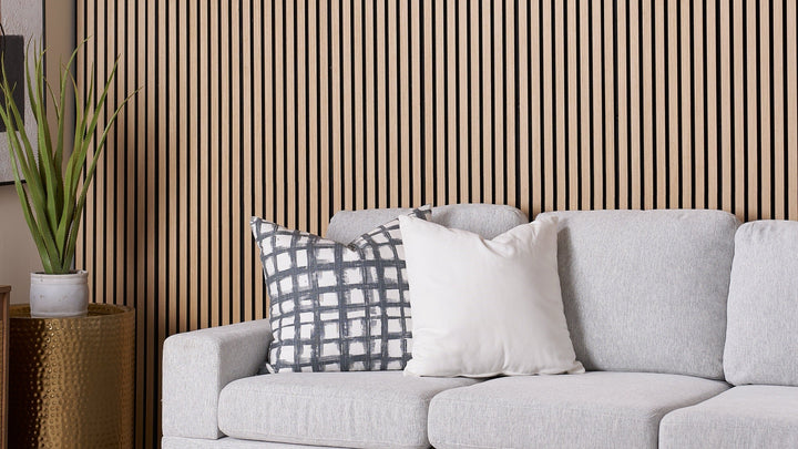 ZETY natural oak acoustic slat wall panels behind a gray sofa in a living room