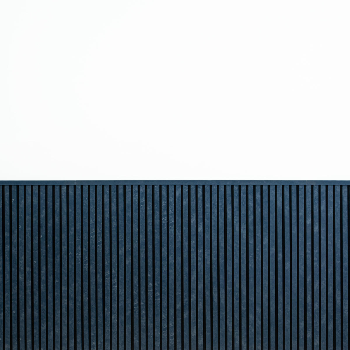 Blue wainscot slat panels finished with top molding against a white upper wall